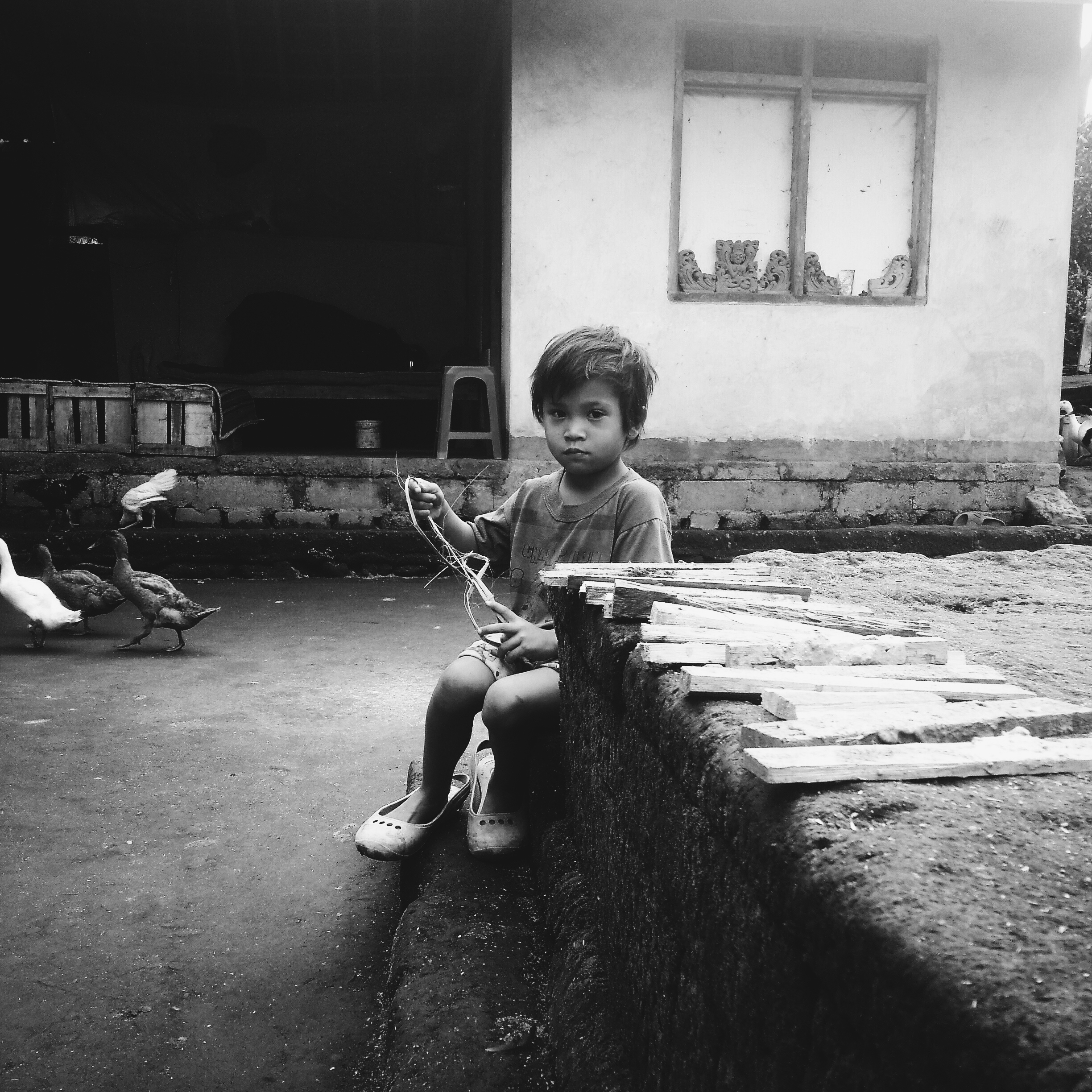 A child playing with planks of wood in the Balinese house